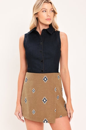 A woman wearing a camel wrap-style mini skort with a navy and white geometric diamond pattern | Flying Tomato