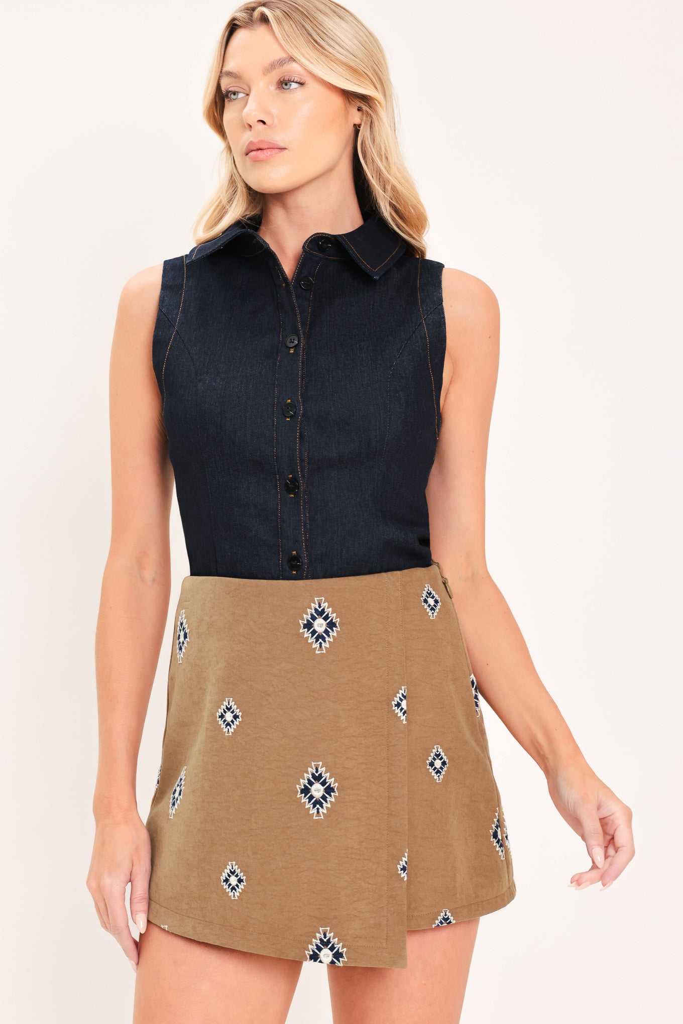 A woman wearing a camel wrap-style mini skort with a navy and white geometric diamond pattern | Flying Tomato