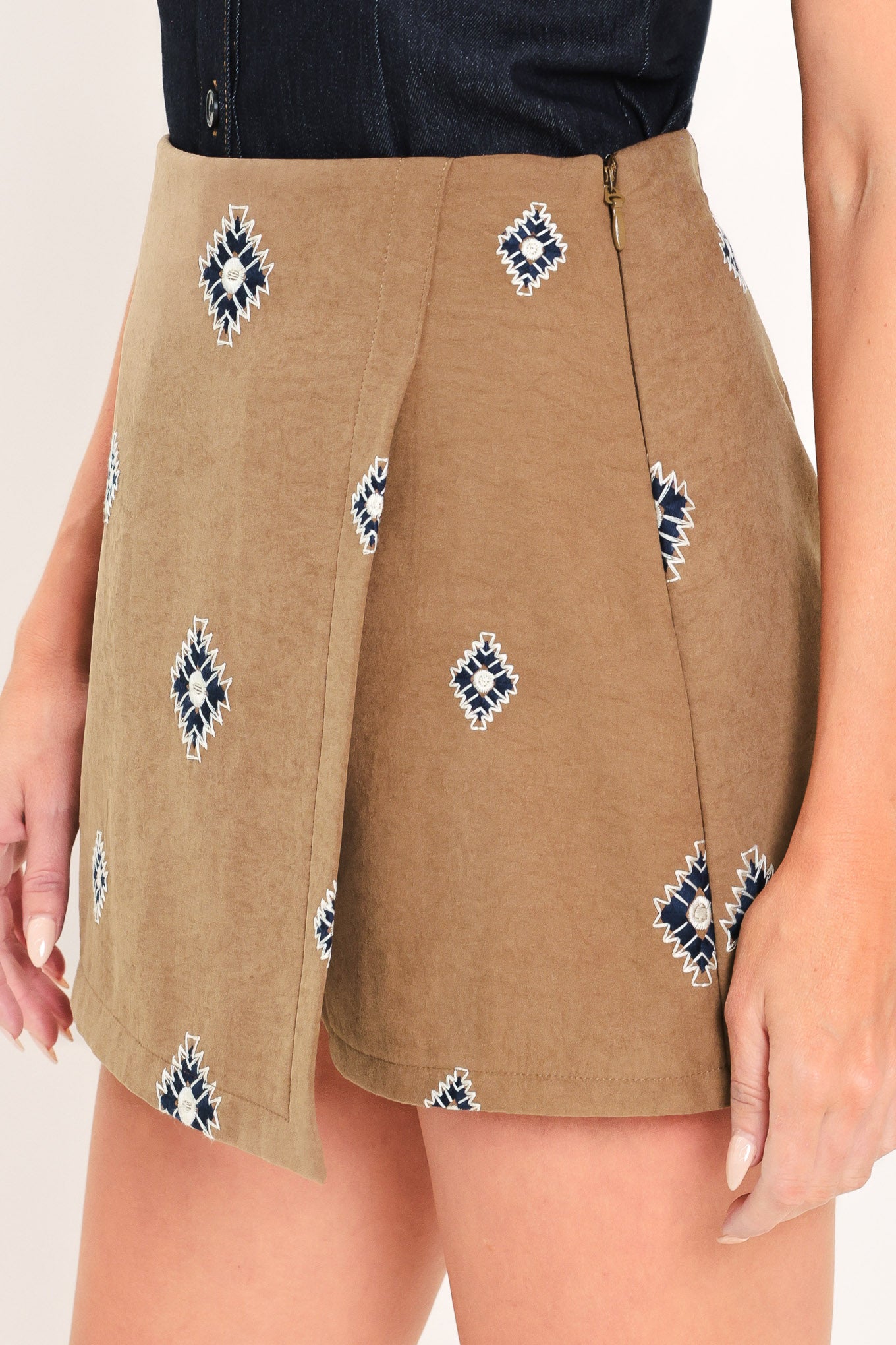 A woman wearing a camel wrap-style mini skort with a navy and white geometric diamond pattern | Flying Tomato