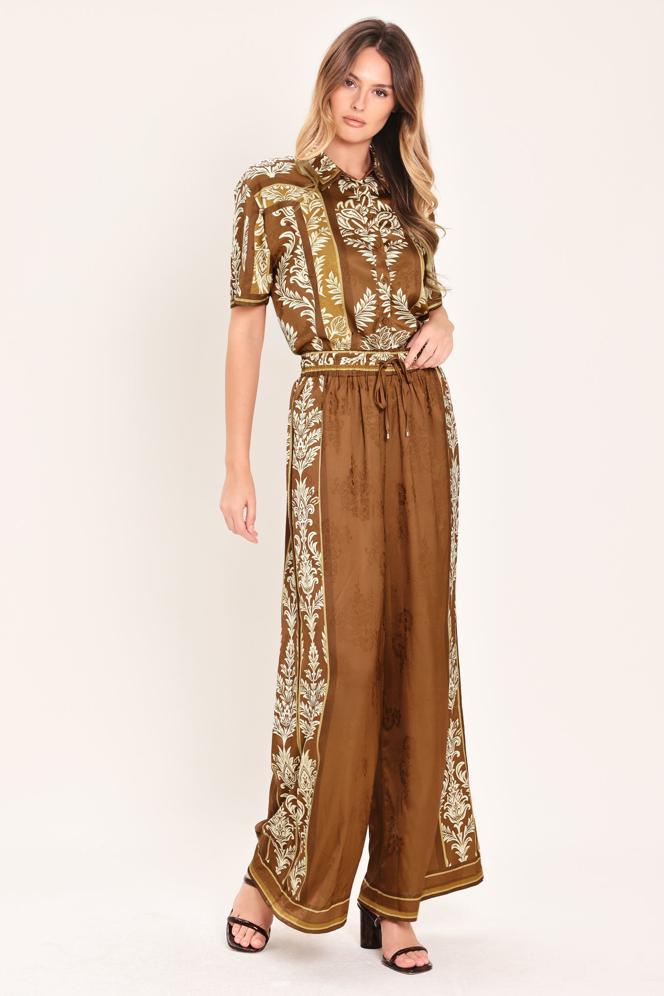 Woman wearing camel brown wide-leg pants with white floral embroidery on the side and waistband | Flying Tomato