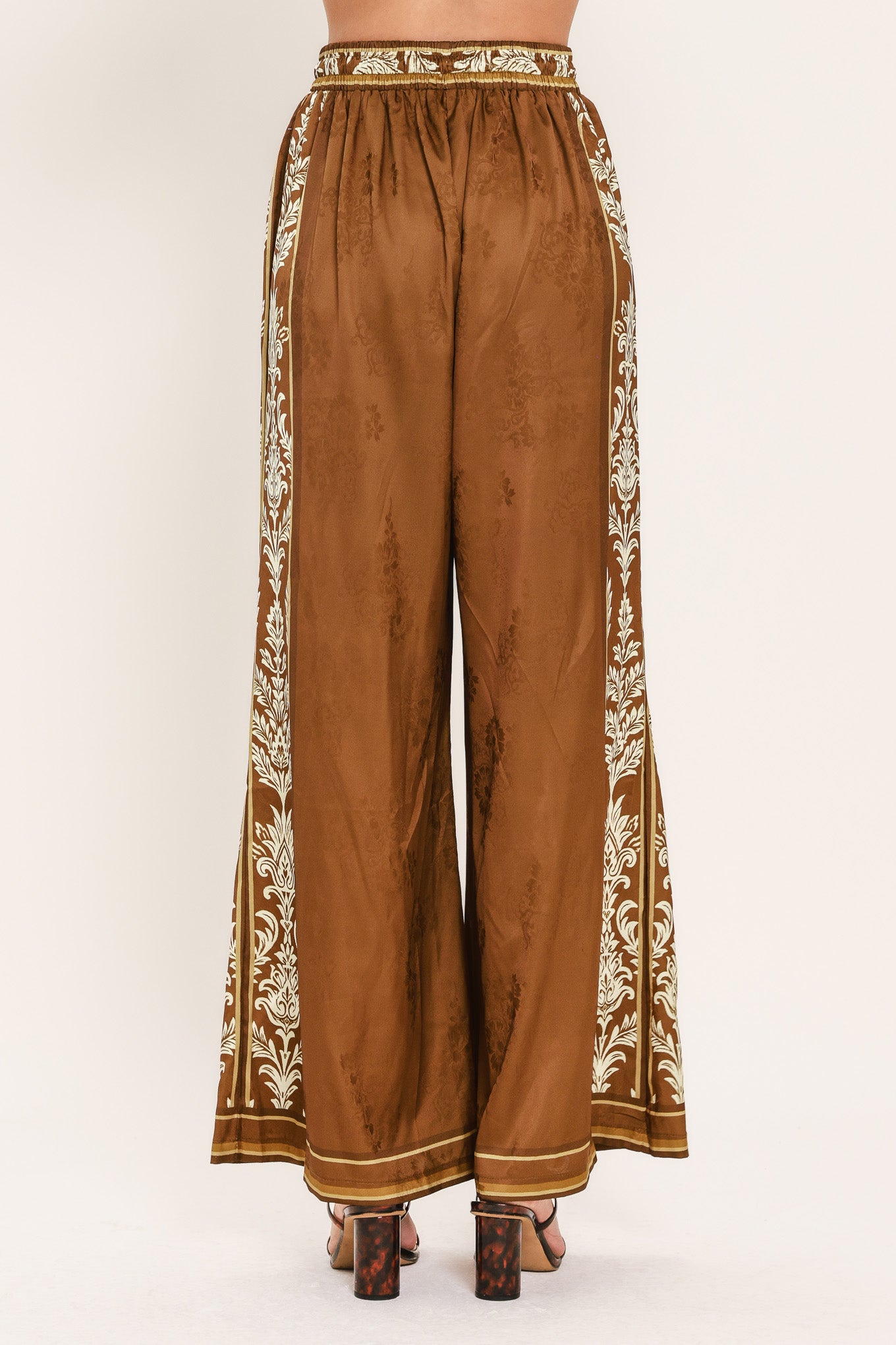 Woman wearing camel brown wide-leg pants with white floral embroidery on the side and waistband | Flying Tomato