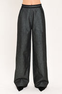A pair of wide-leg trousers in a black denim textured fabric, shown on a model | Flying Tomato