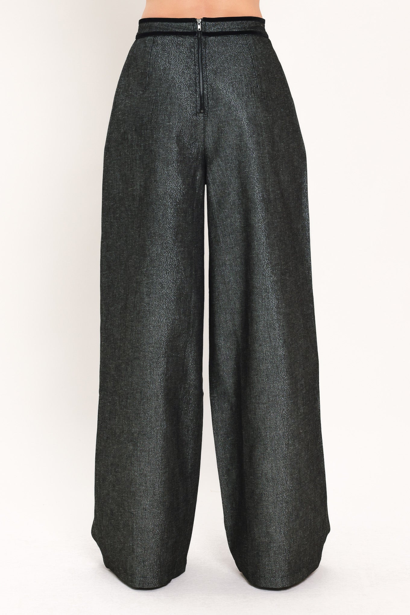 A pair of wide-leg trousers in a black denim textured fabric, shown on a model | Flying Tomato