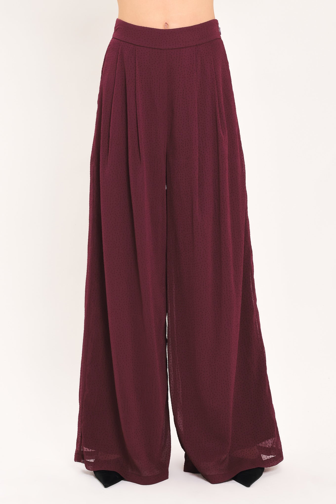 A pair of wide-leg, high-waisted trousers in a deep burgundy or maroon fabric, shown on a model | Flying Tomato