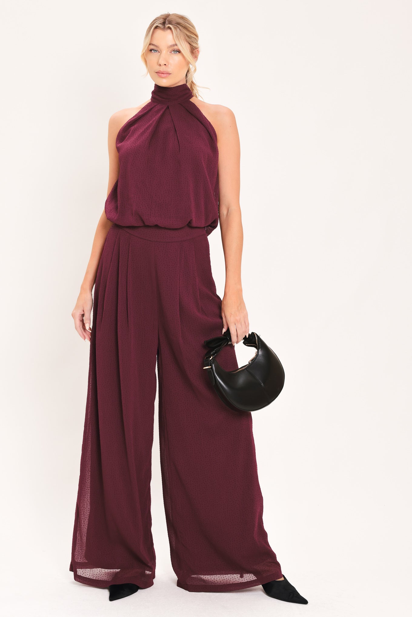 A pair of wide-leg, high-waisted trousers in a deep burgundy or maroon fabric, shown on a model | Flying Tomato