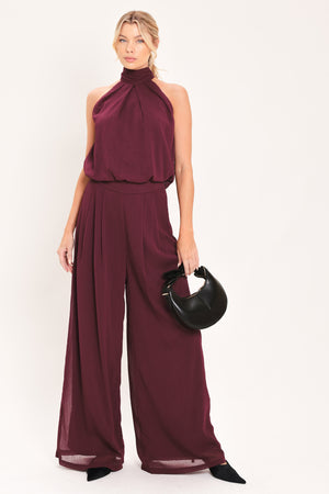 A pair of wide-leg, high-waisted trousers in a deep burgundy or maroon fabric, shown on a model | Flying Tomato