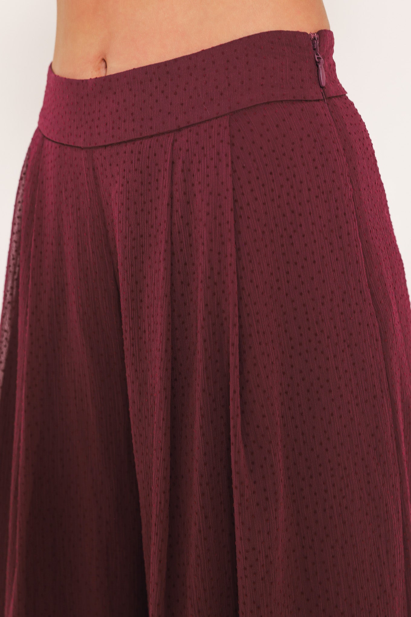 A pair of wide-leg, high-waisted trousers in a deep burgundy or maroon fabric, shown on a model | Flying Tomato