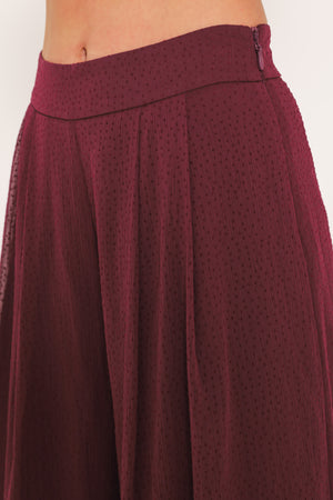 A pair of wide-leg, high-waisted trousers in a deep burgundy or maroon fabric, shown on a model | Flying Tomato