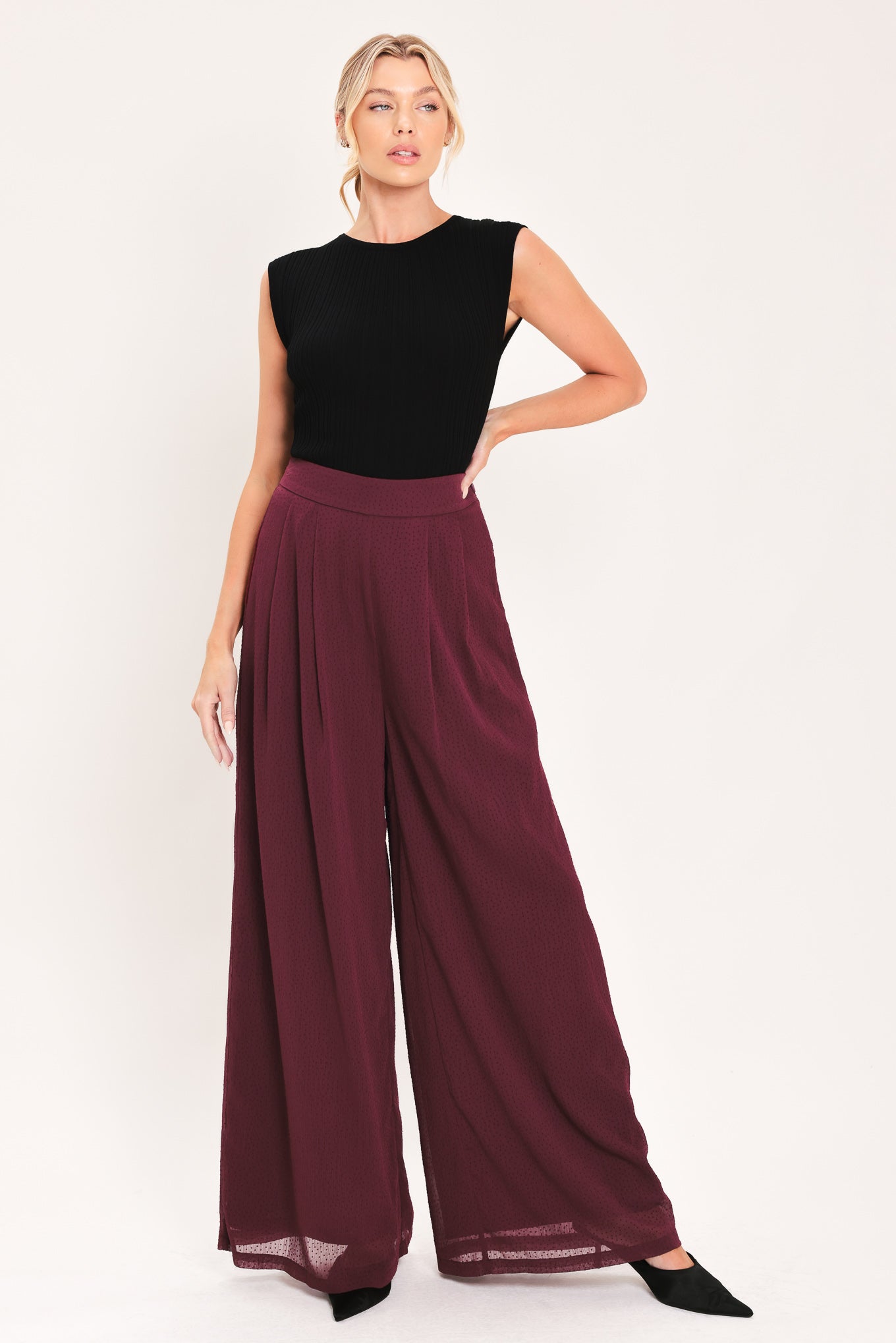 A pair of wide-leg, high-waisted trousers in a deep burgundy or maroon fabric, shown on a model | Flying Tomato