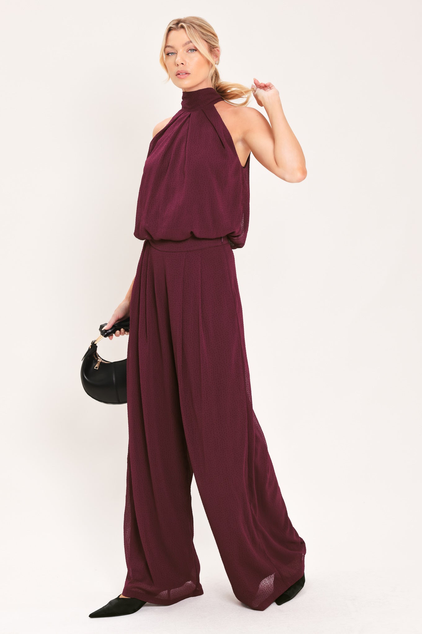A pair of wide-leg, high-waisted trousers in a deep burgundy or maroon fabric, shown on a model | Flying Tomato