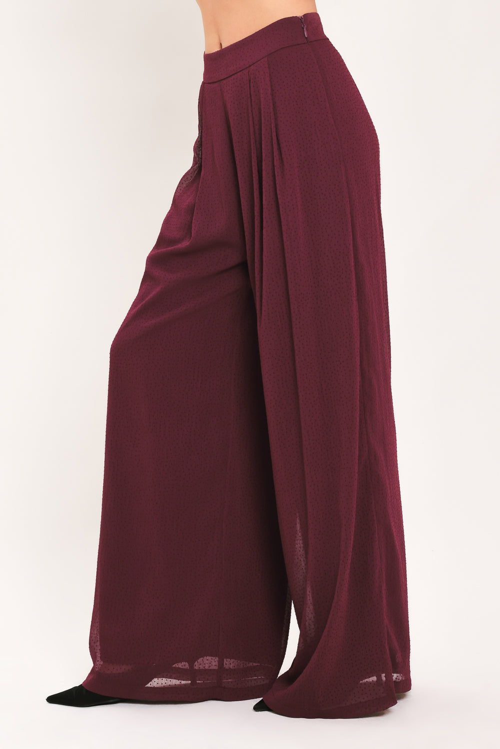 A pair of wide-leg, high-waisted trousers in a deep burgundy or maroon fabric, shown on a model | Flying Tomato