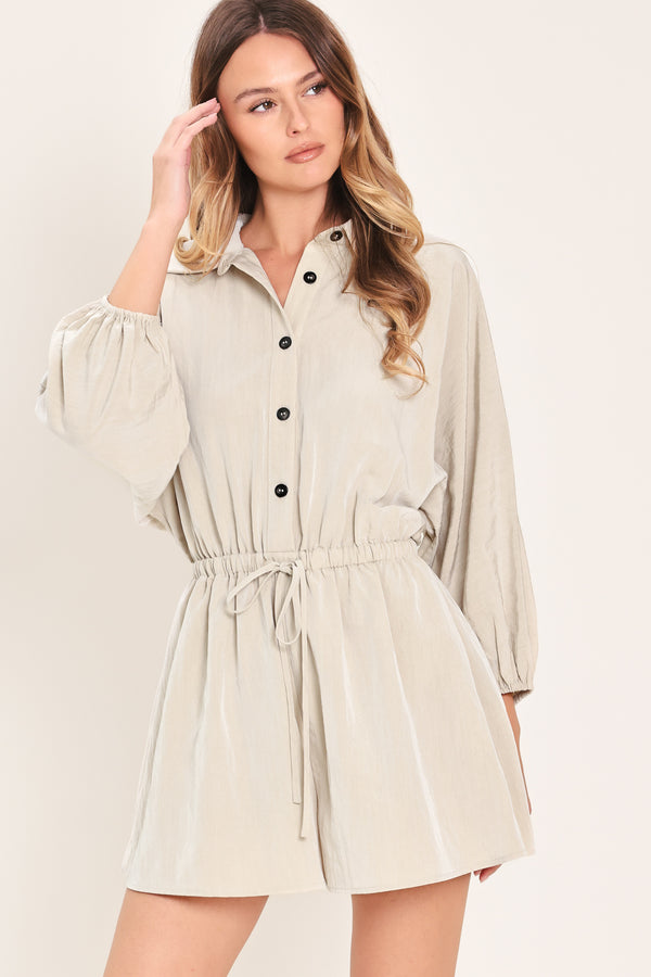Woman wearing a light gray, stone colored romper featuring collar, front button down, 3/4 dolman sleeve and elastic waist with tie | Flying Tomato