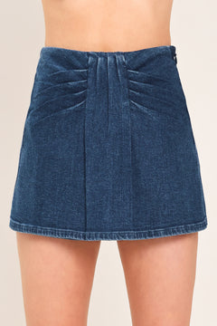 A close-up of a model wearing a dark blue denim mini skort with pleated detailing at the waistband | Flying Tomato