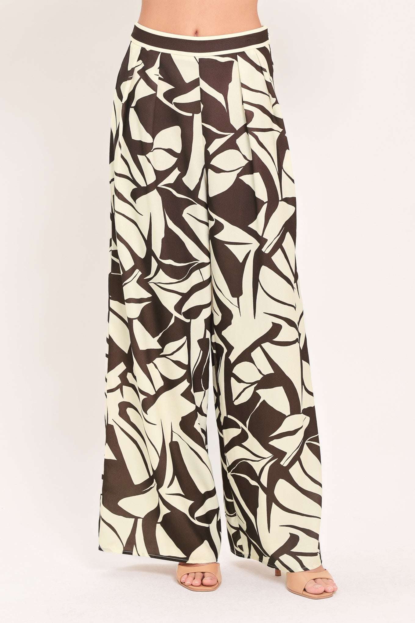 A woman wearing loose, wide-leg pants with an abstract leaf-like print in dark brown and off-white | Flying Tomato