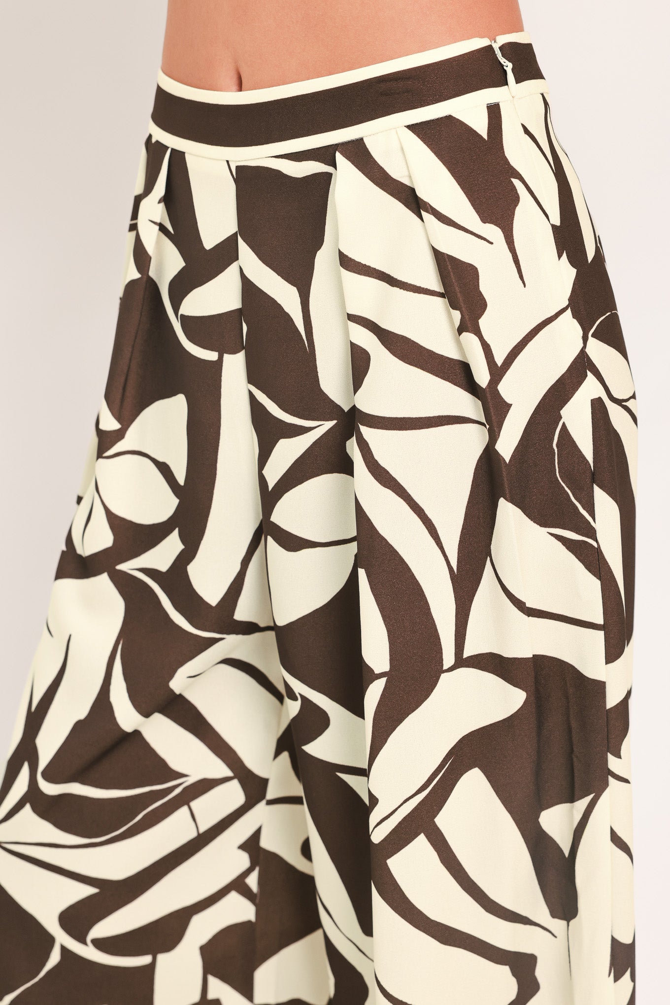 A woman wearing loose, wide-leg pants with an abstract leaf-like print in dark brown and off-white | Flying Tomato