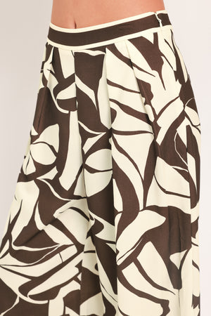 A woman wearing loose, wide-leg pants with an abstract leaf-like print in dark brown and off-white | Flying Tomato