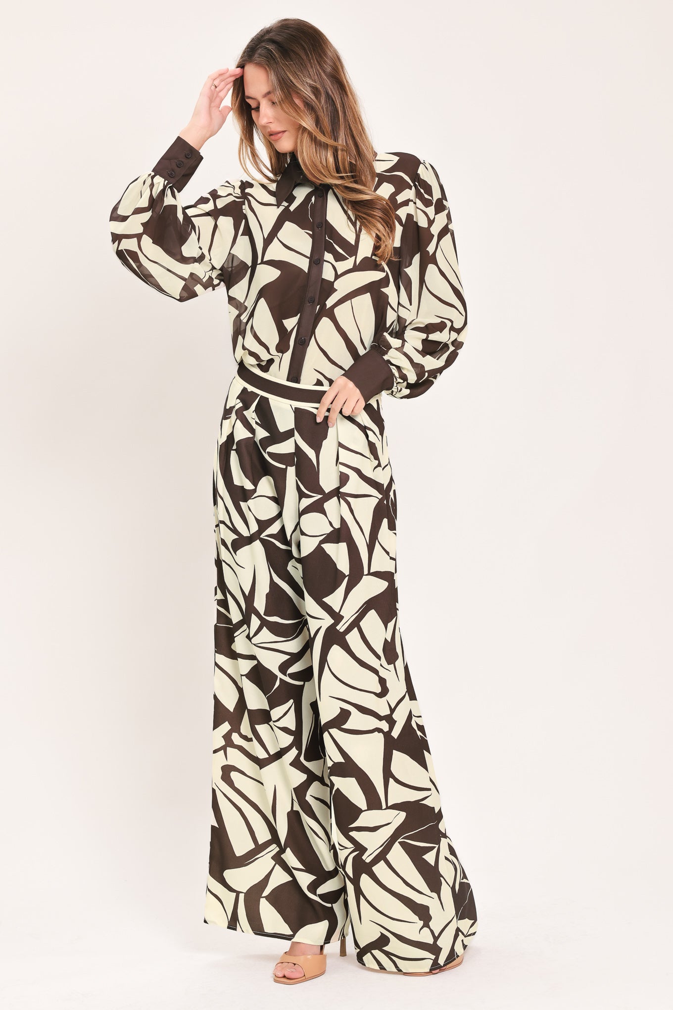 A woman wearing loose, wide-leg pants with an abstract leaf-like print in dark brown and off-white | Flying Tomato