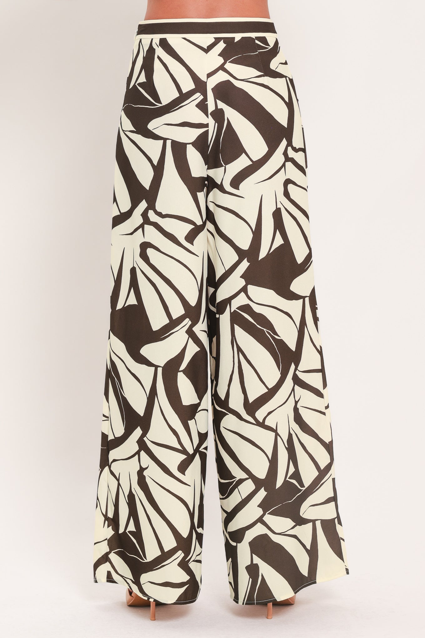 A woman wearing loose, wide-leg pants with an abstract leaf-like print in dark brown and off-white | Flying Tomato
