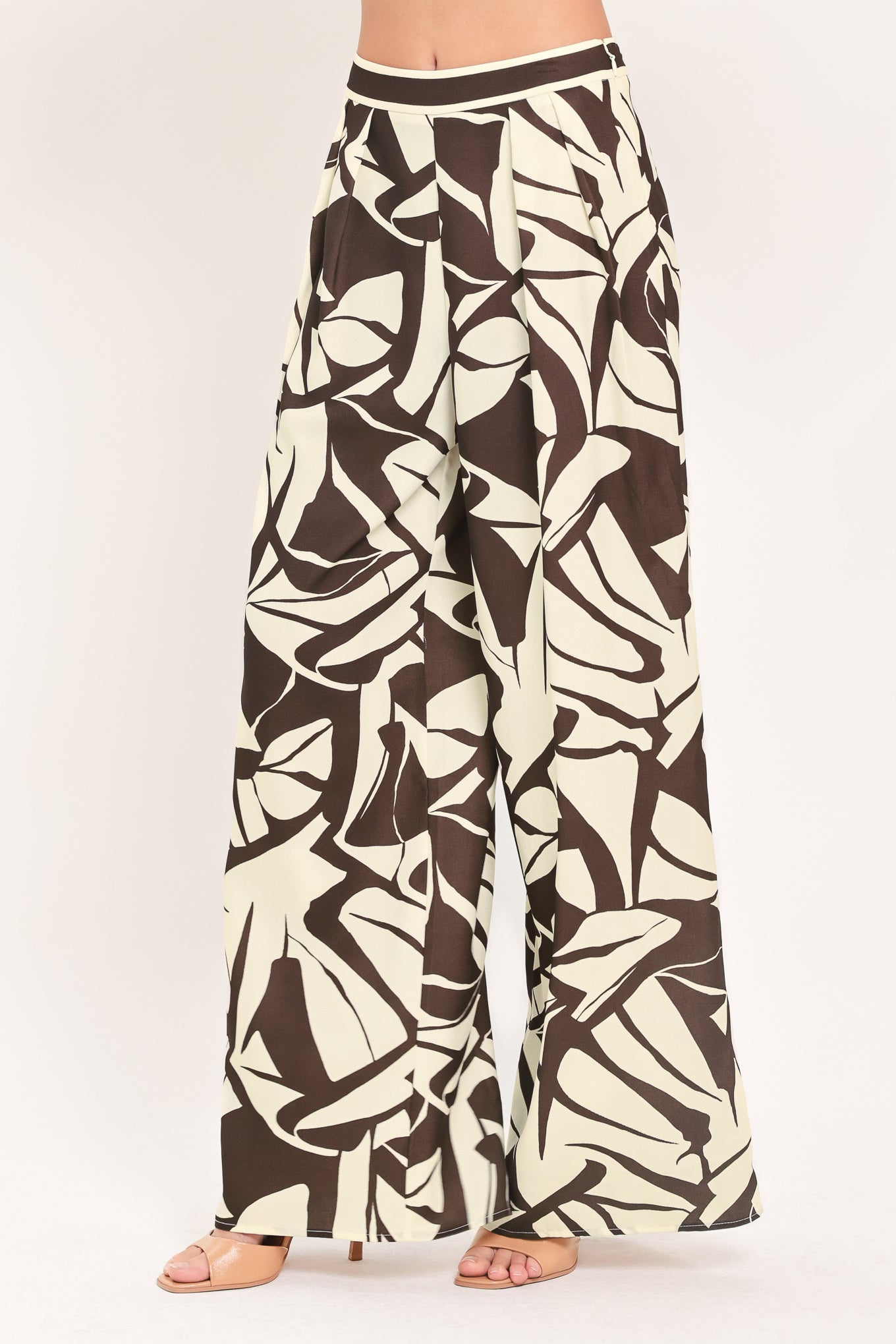 A woman wearing loose, wide-leg pants with an abstract leaf-like print in dark brown and off-white | Flying Tomato