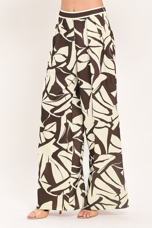 A woman wearing loose, wide-leg pants with an abstract leaf-like print in dark brown and off-white | Flying Tomato