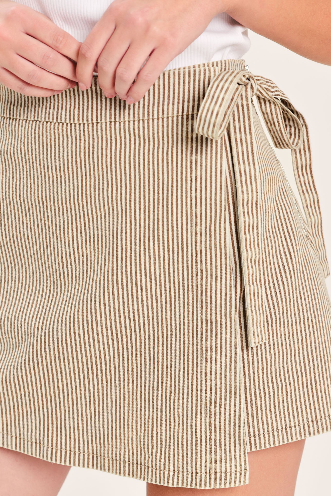 Woman wearing a brown striped woven skort featuring side tie and zipper closure | Flying Tomato