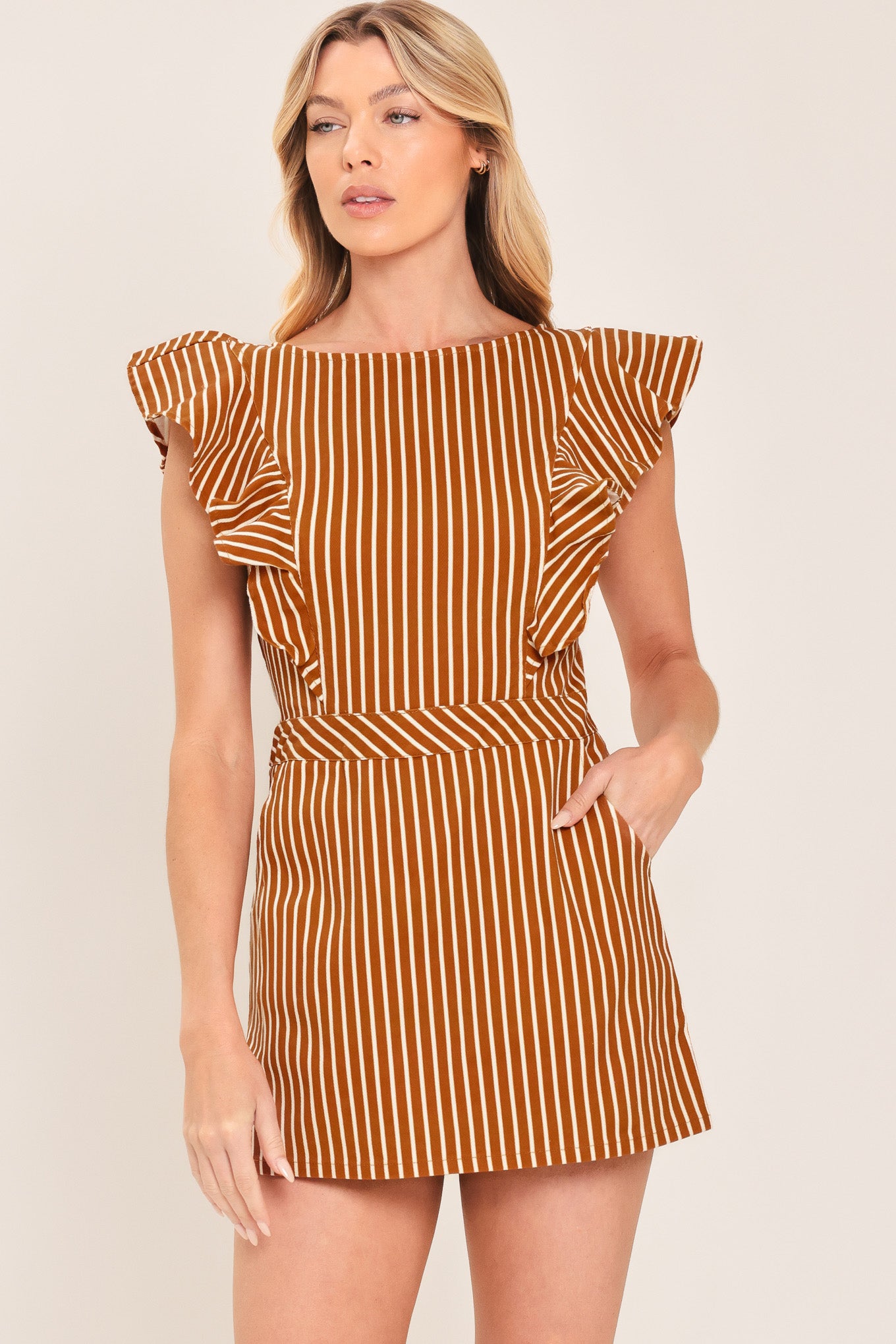 A woman wearing a mini skort romper with vertical rust and white stripes | Flying Tomato