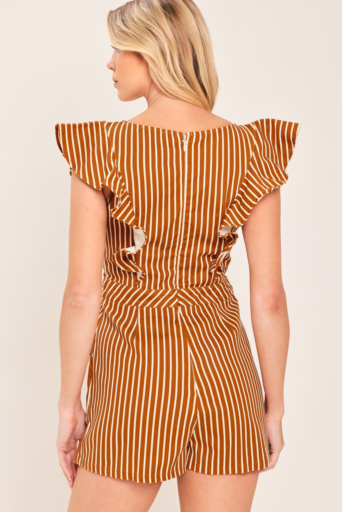 A woman wearing a mini skort romper with vertical rust and white stripes | Flying Tomato