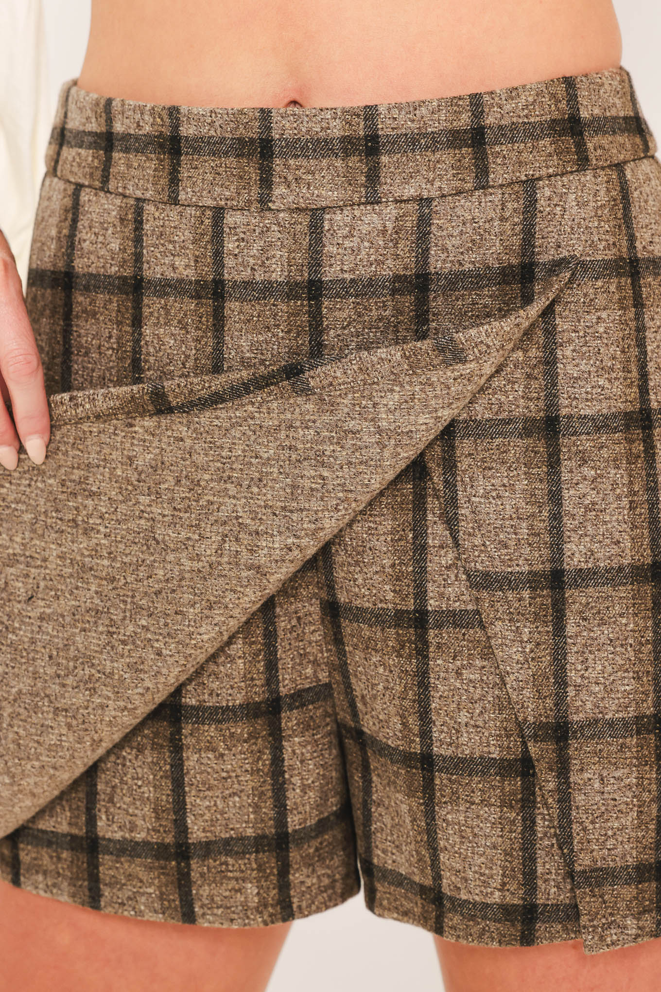 A woman wearing a taupe and brown plaid skort | Flying Tomato