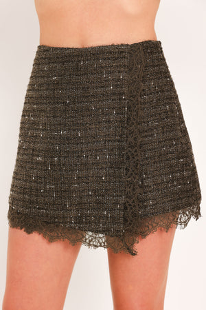 A close-up of a model wearing a dark brown tweed mini skort with a lace hem and a lace side detail | Flying Tomato
