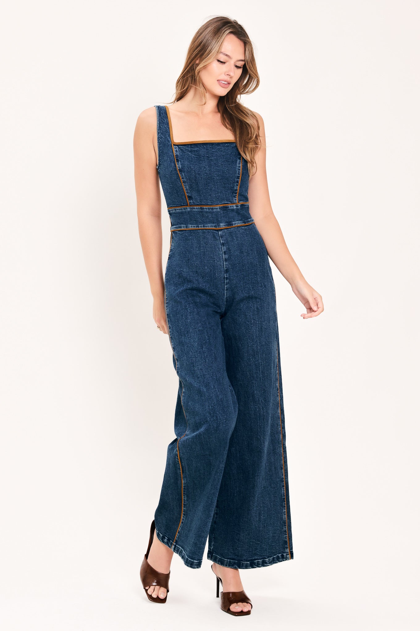 A woman modeling a dark blue denim wide-leg jumpsuit with square neckline | Flying Tomato