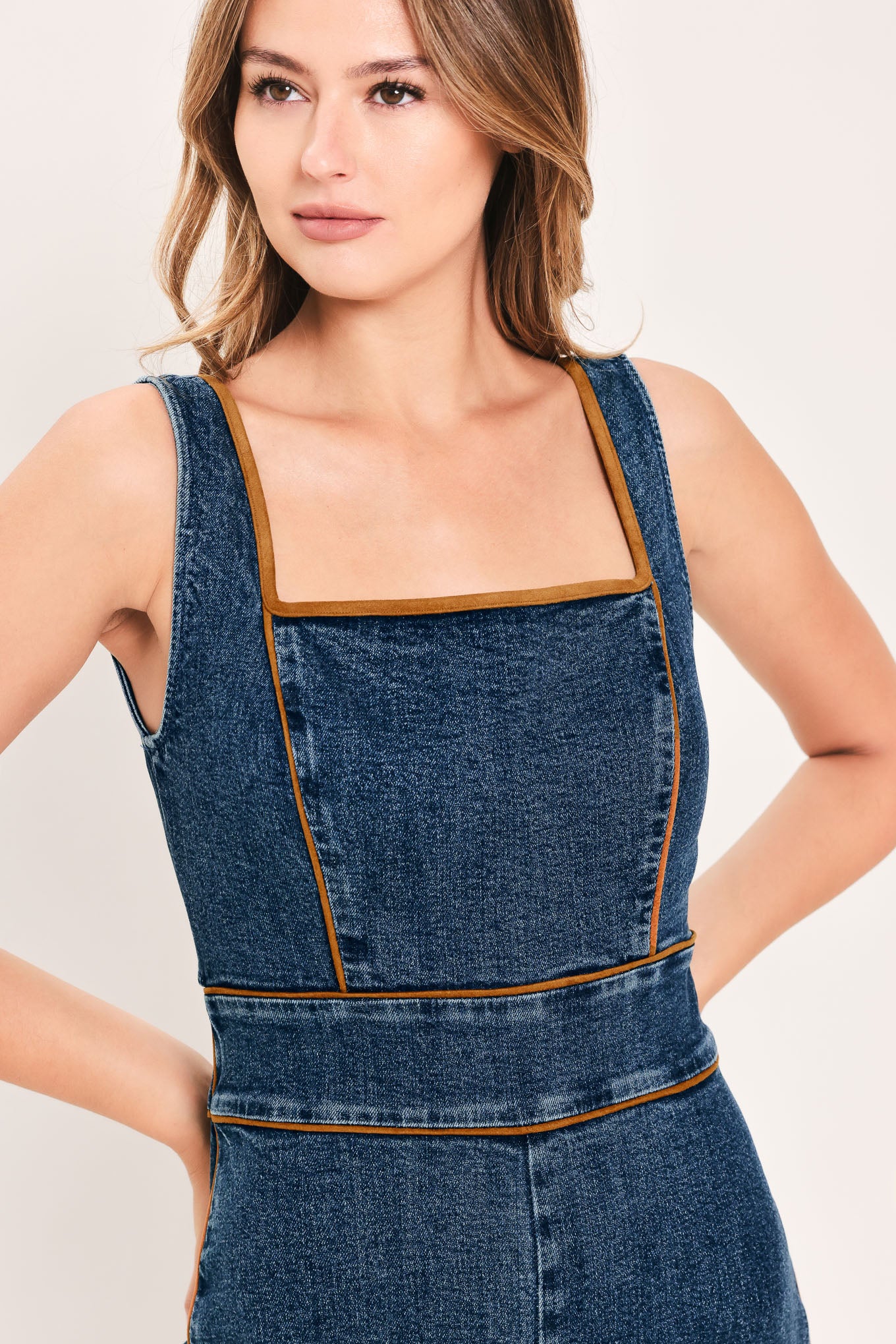 A woman modeling a dark blue denim wide-leg jumpsuit with square neckline | Flying Tomato