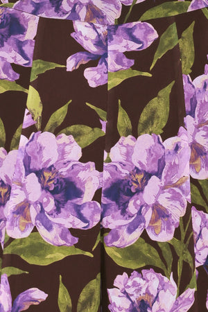 A model is wearing a pair of wide-leg, high-waisted pants featuring a bold purple floral print on a dark brown background | Flying Tomato