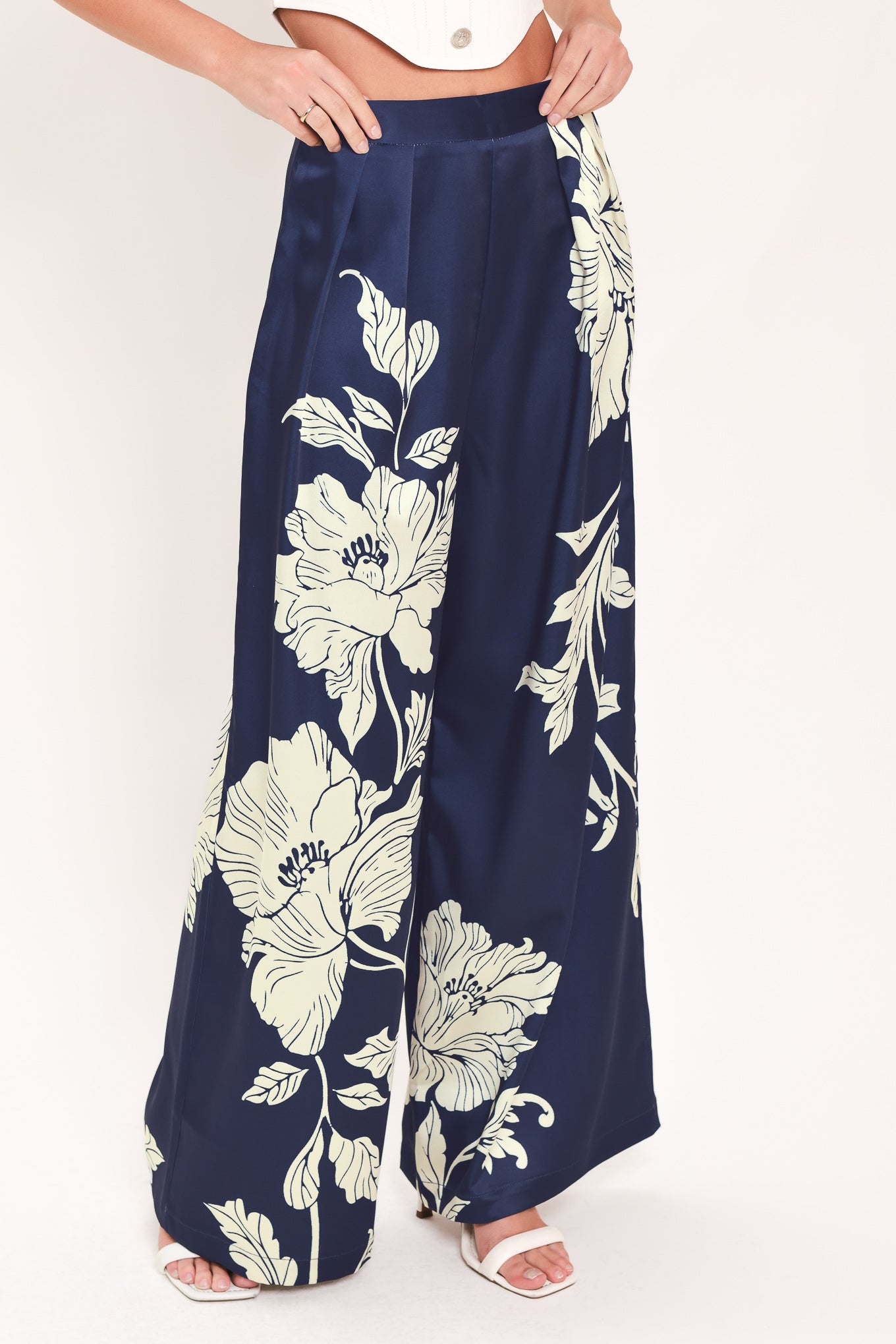 A woman wearing navy blue wide-leg pants with a large cream floral print | Flying Tomato