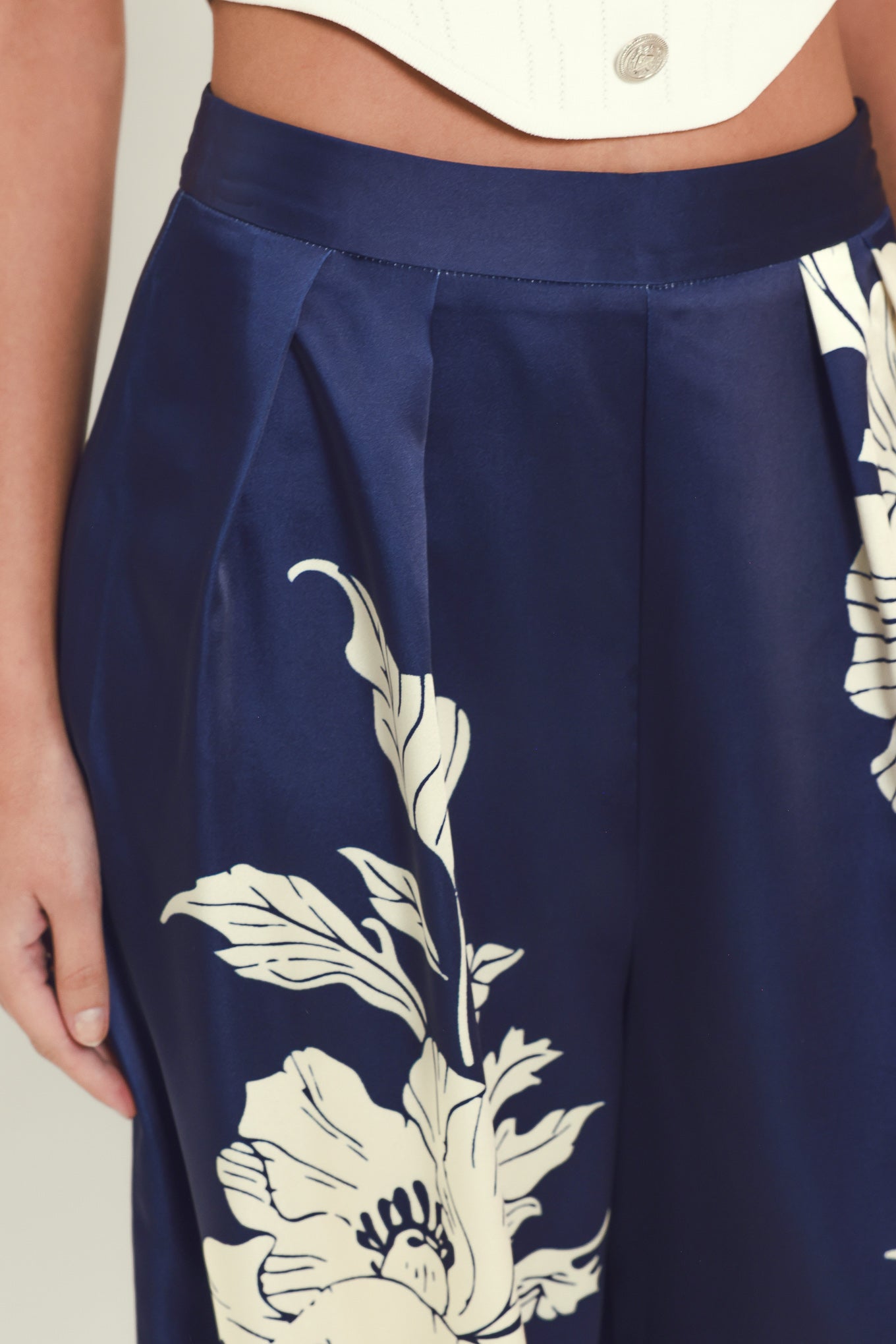A woman wearing navy blue wide-leg pants with a large cream floral print | Flying Tomato