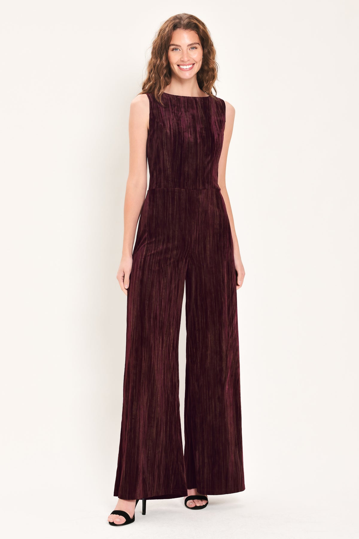 Woman wearing a sleeveless burgundy velvet jumpsuit with wide-leg pants | Flying Tomato