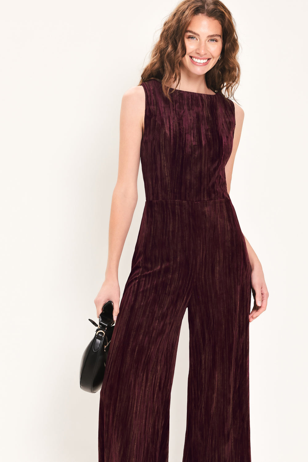 Woman wearing a sleeveless burgundy velvet jumpsuit with wide-leg pants | Flying Tomato