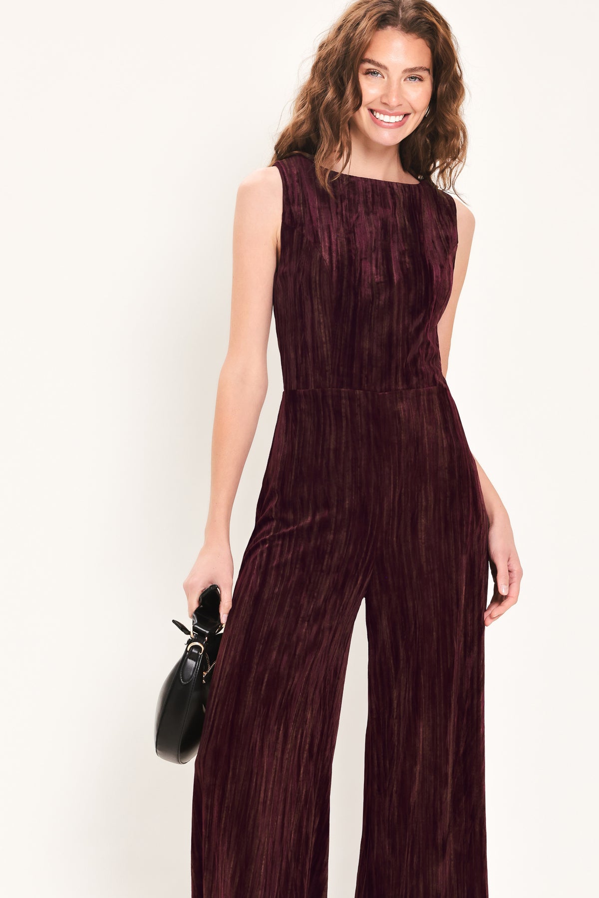 Woman wearing a sleeveless burgundy velvet jumpsuit with wide-leg pants | Flying Tomato