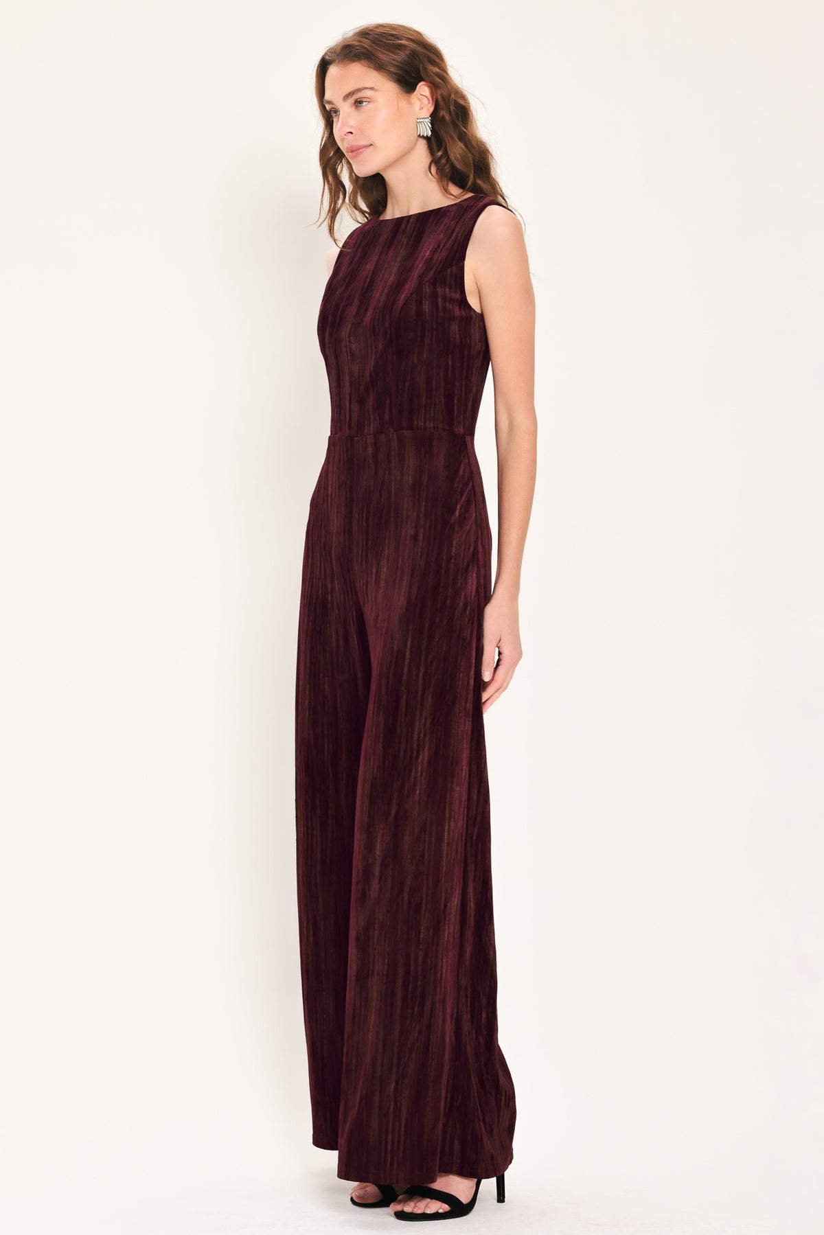 Woman wearing a sleeveless burgundy velvet jumpsuit with wide-leg pants | Flying Tomato
