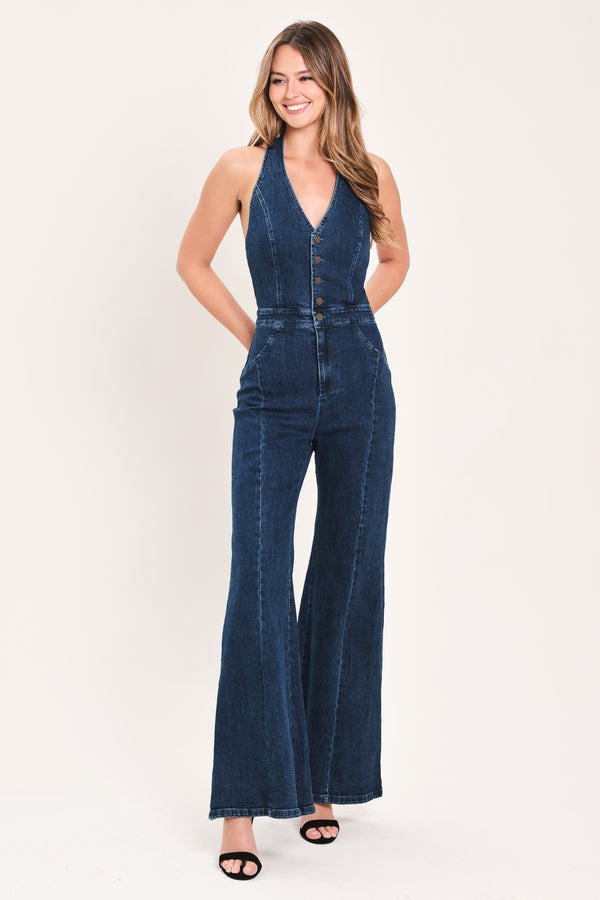 A woman wearing a dark blue denim halter jumpsuit with a button-front bodice and wide flared legs | Flying Tomato 