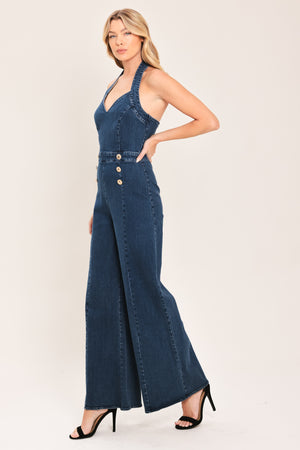 Woman wearing a denim jumpsuit featuring halter neckline, front button detail, wide leg, bare back and zipper closure | Flying Tomato
