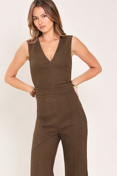 Woman wearing a brown jumpsuit featuring V neckline, sleeveless, flare leg, back cut out and button zipper closure | Flying Tomato
