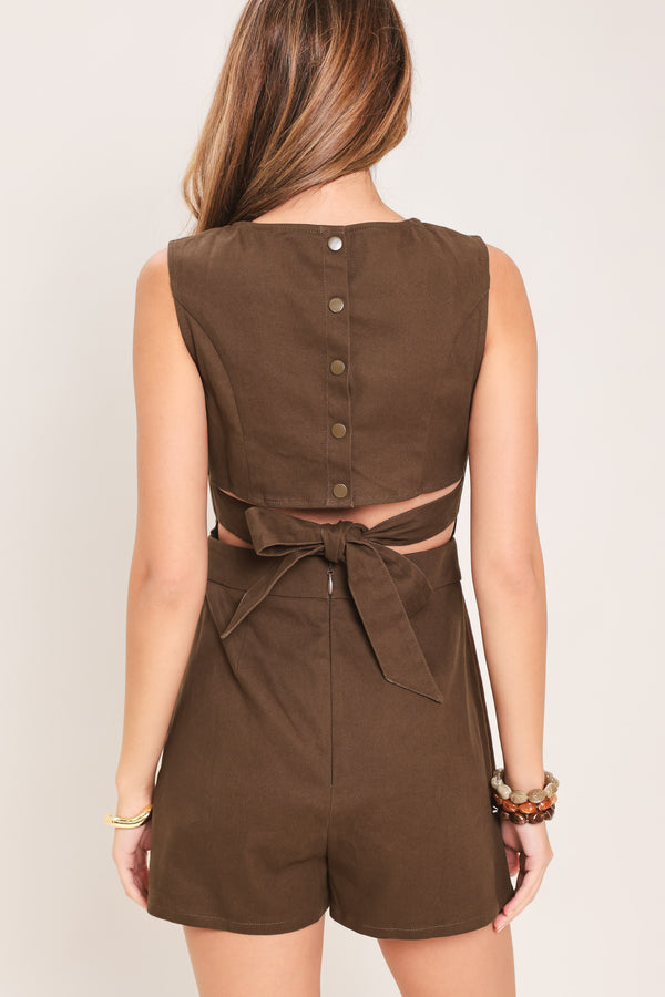 Woman wearing a brown woven skort romper featuring round neckline, sleeveless, back cut out with tie and button zipper closure | Flying Tomato