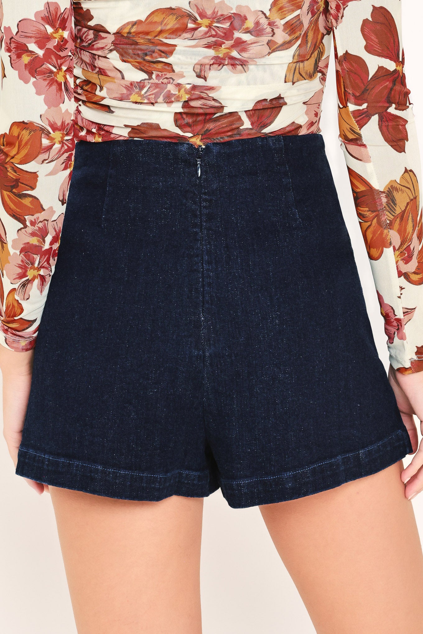Woman wearing a dark denim skort with side pleat and back zipper closure | Flying Tomato