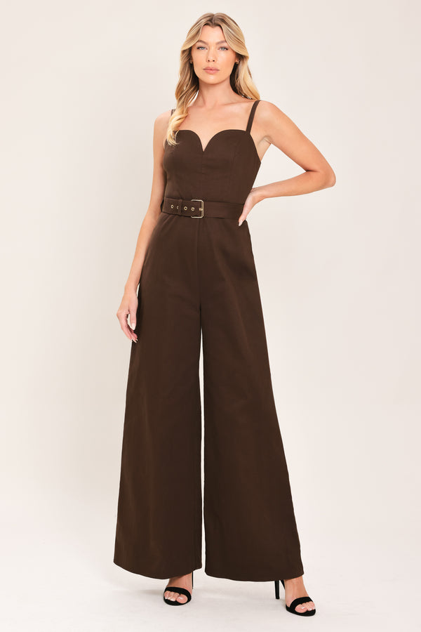 Woman wearing a brown solid woven jumpsuit featuring sweetheart neckline, straps, self belt, wide leg and back zipper closure | Flying Tomato