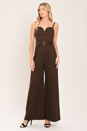Woman wearing a brown solid woven jumpsuit featuring sweetheart neckline, straps, self belt, wide leg and back zipper closure | Flying Tomato