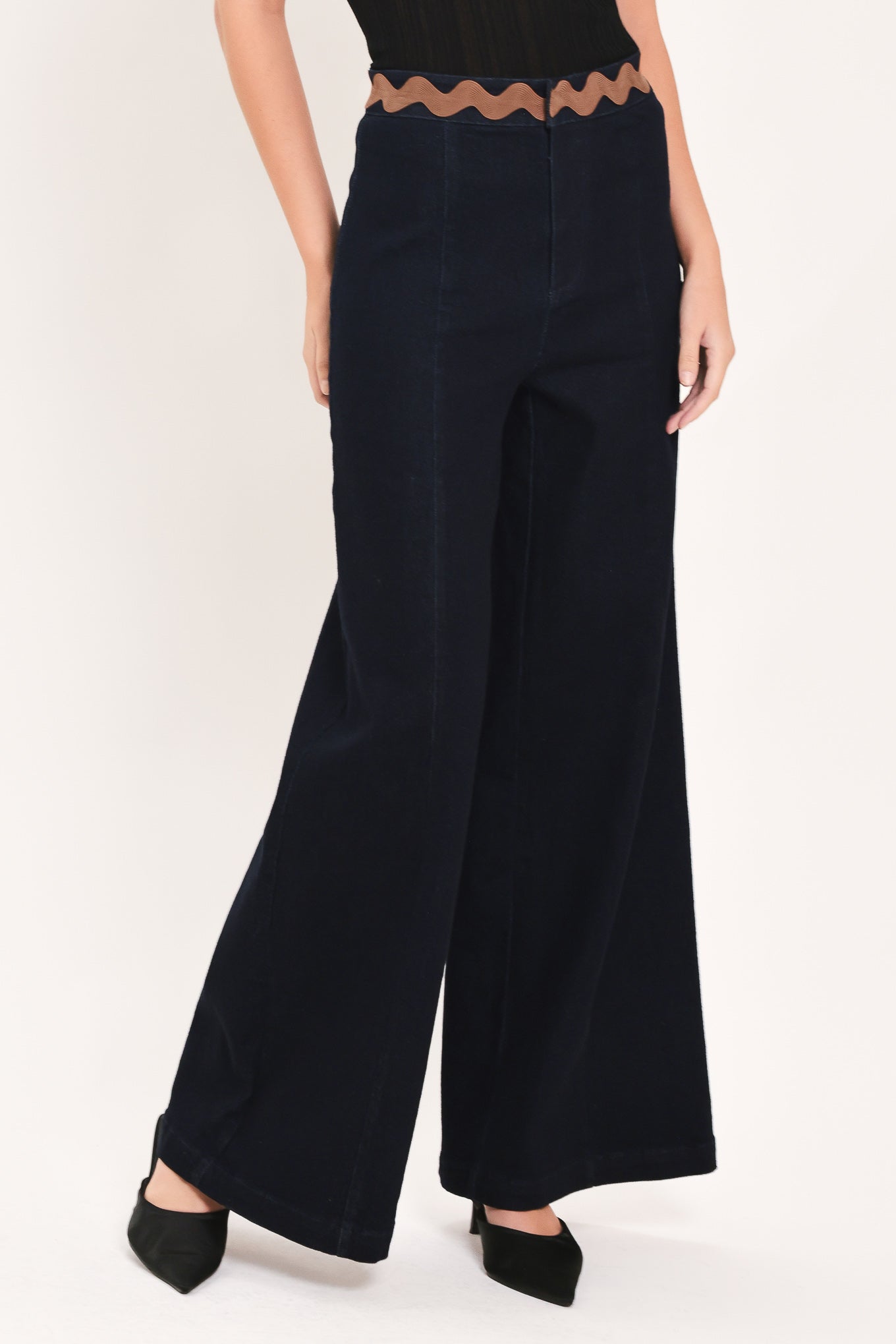 A model is wearing a pair of wide-leg navy blue pants with a distinctive scalloped brown waistband | Flying Tomato