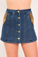 A blue denim mini skort with a button-front closure and brown suede-like side pockets, shown on a model | Flying Tomato