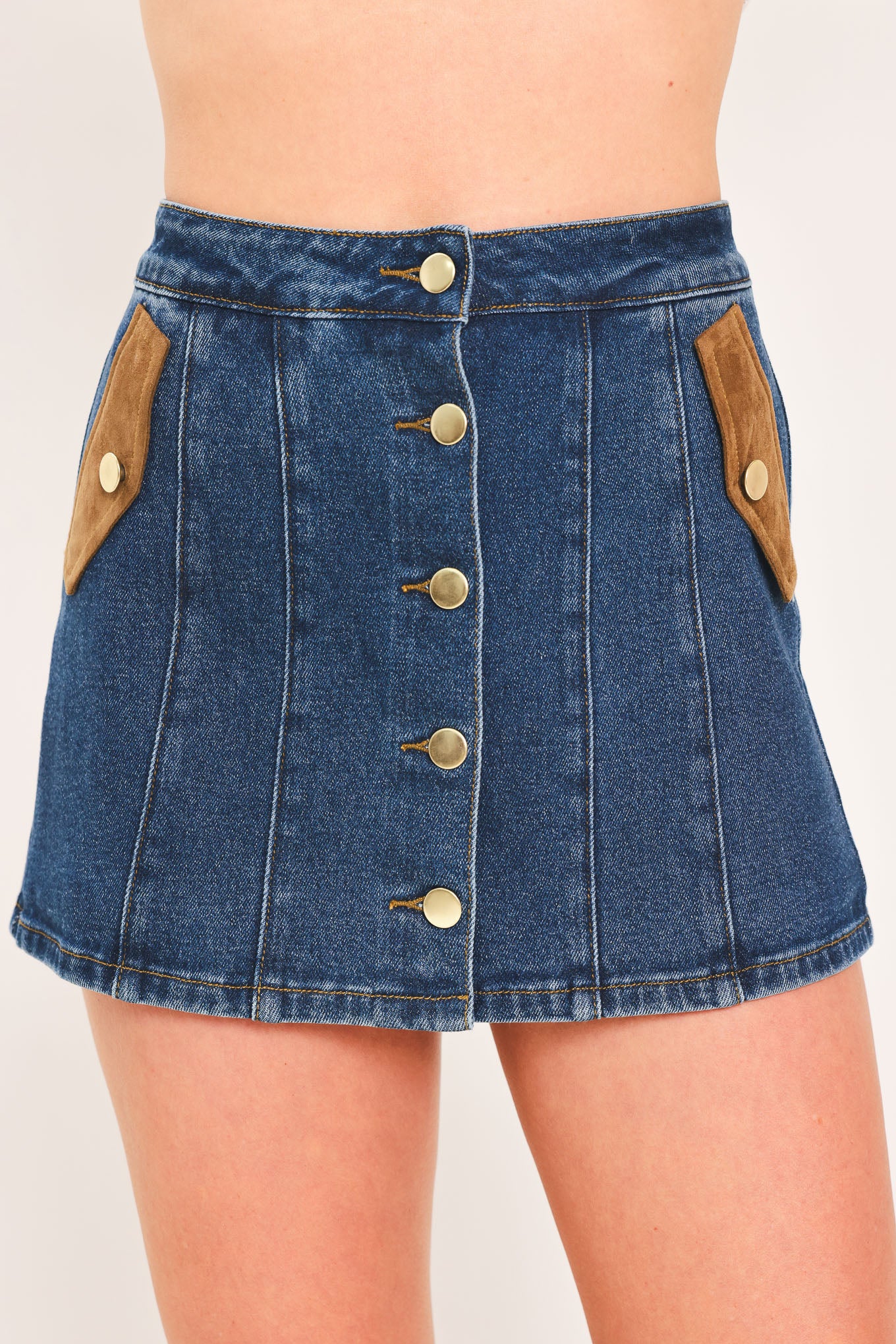 A blue denim mini skort with a button-front closure and brown suede-like side pockets, shown on a model | Flying Tomato