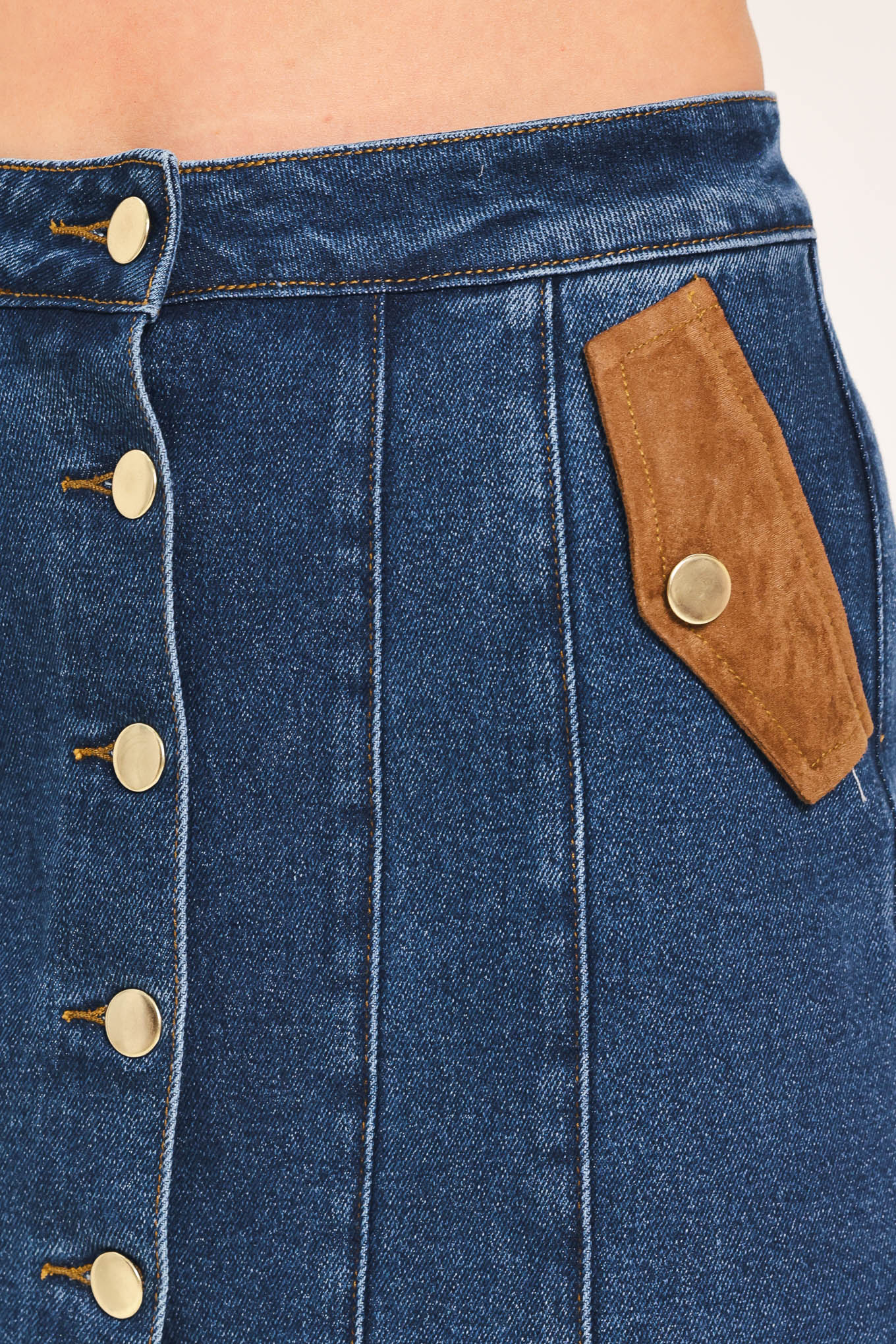 A blue denim mini skort with a button-front closure and brown suede-like side pockets, shown on a model | Flying Tomato