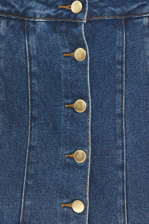 A blue denim mini skort with a button-front closure and brown suede-like side pockets, shown on a model | Flying Tomato